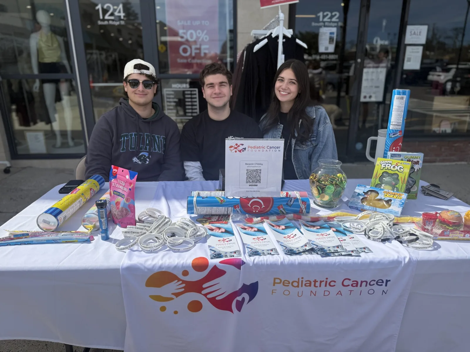 Volunteers hosting a PCF fundraiser table with bracelets and candy